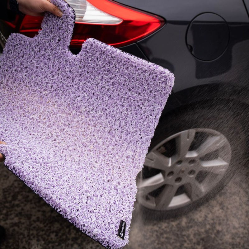 Real CarMatsCulture customer holding colourful Honeycomb Mats beside a vehicle