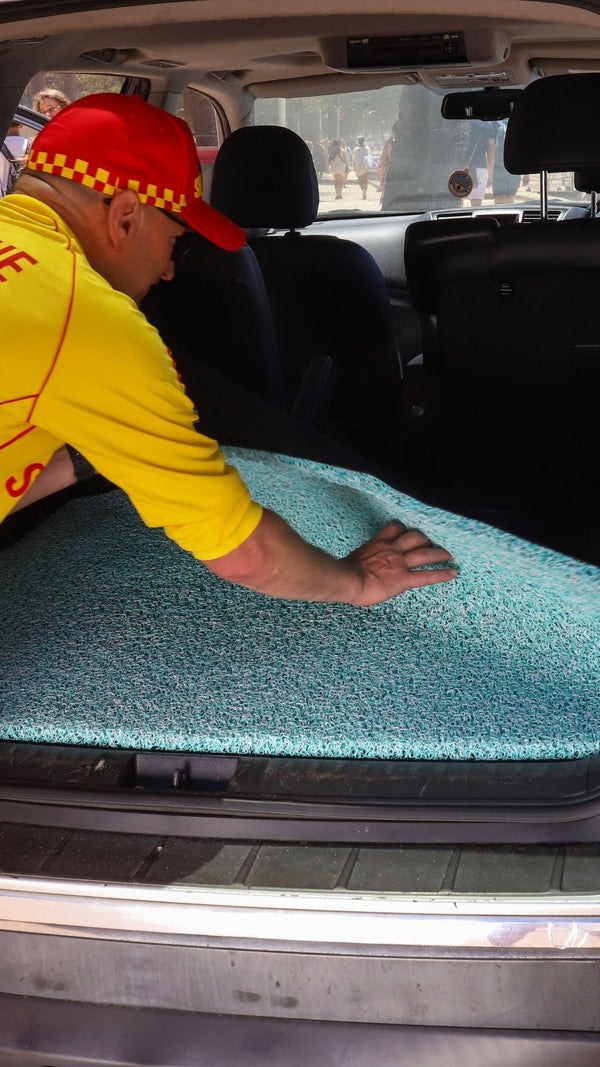 CarMatsCulture customer handling a real Honeycomb Mat beside a vehicle